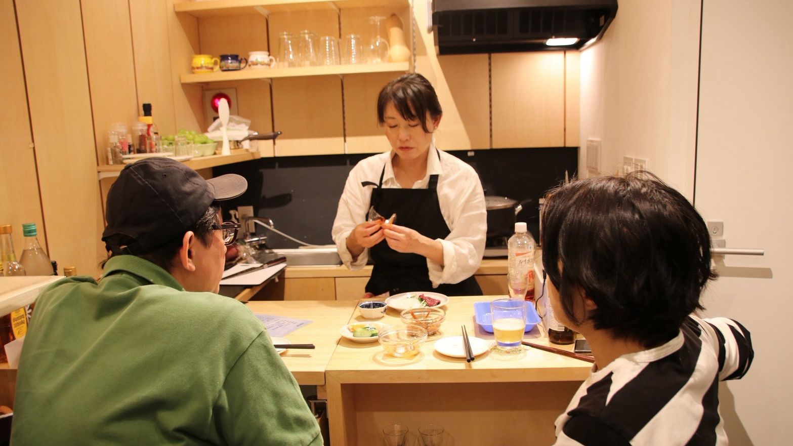 カウンター越しに料理を仕上げる店主とお客様